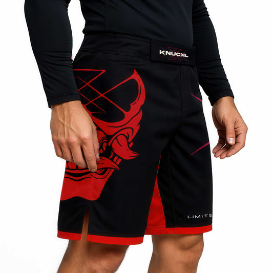 Side view of Knuckl MMA shorts with red trim and demon artwork